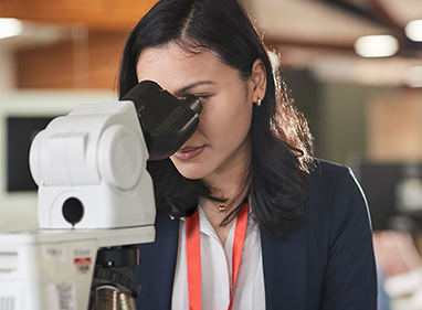 Female laboratory technician looking in microscope