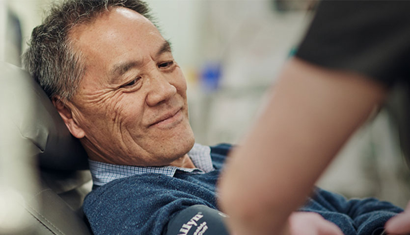 a donor is sitting in a chair and smiling while a nurse assists him