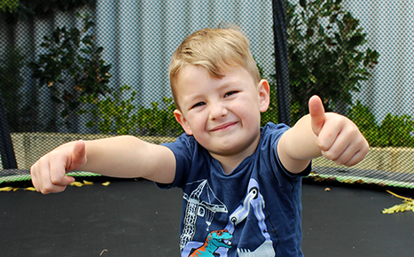 boy on trampoline smiling with both thumbs up