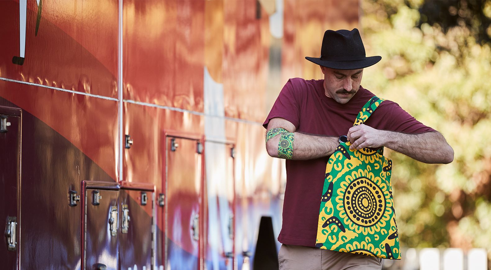 a man is wearing a tote bag around his shoulder, the tote bag is featuring the brad hore design