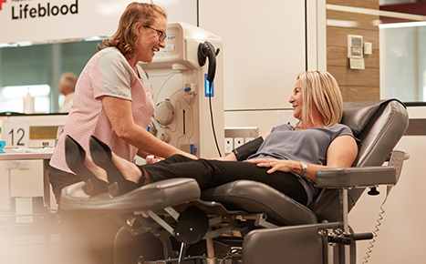 A woman sitting in a donor chair talking to a nurse