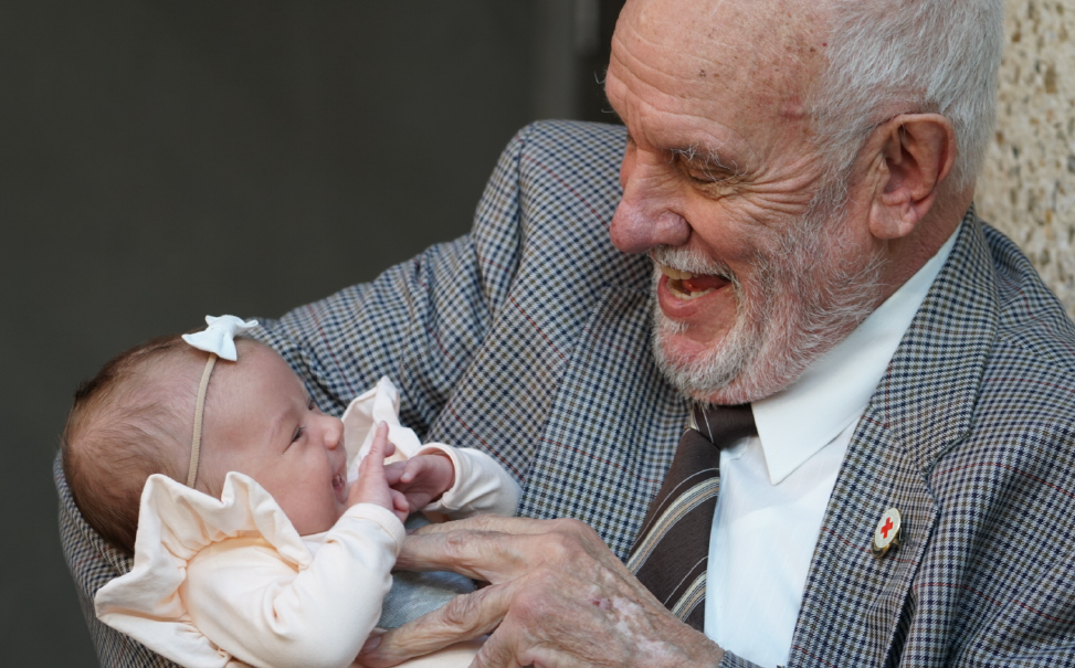 image of an elderly man holding a baby girl wearing a white bow band