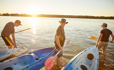 Men carrying kayaks into water