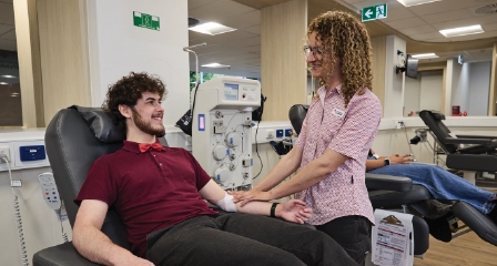 a male in a donation chair smiling and talking with a nurse