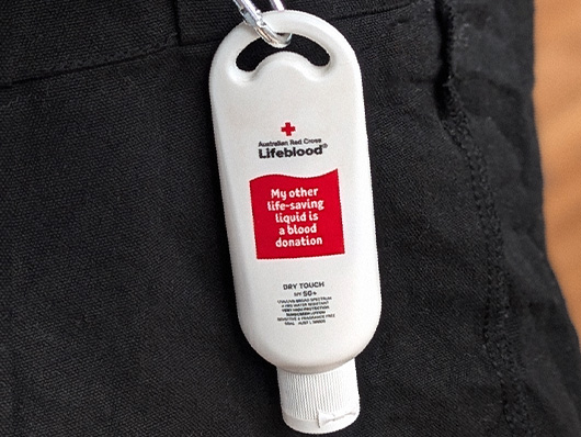 a bottle of lifeblood branded sunscreen clipped to a belt