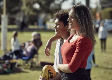 Two people standing in the crowd at a sports field