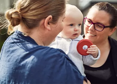 two parents smiling and carrying a baby