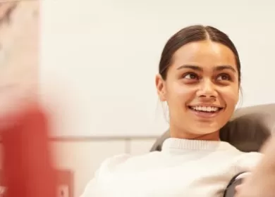 Dark-haired girl smiling at a nurse as she gives blood