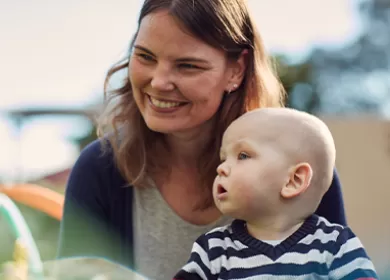 a mother sits with her child on her lap looking off camera and smiling