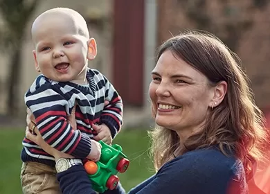 a smiling mother holds up a baby