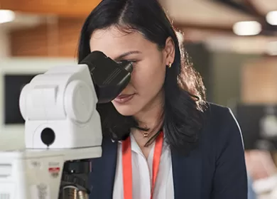 Female laboratory technician looking in microscope