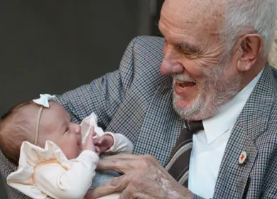 image of an elderly man holding a baby girl wearing a white bow band