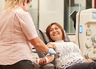 Woman giving blood smiling at nurse