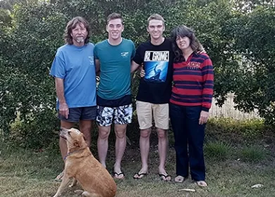 a family of four in a backyard with a dog beside them