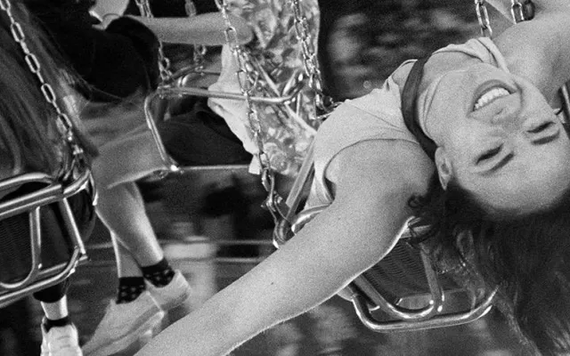 a woman on a fairground ride smiling and leaning back