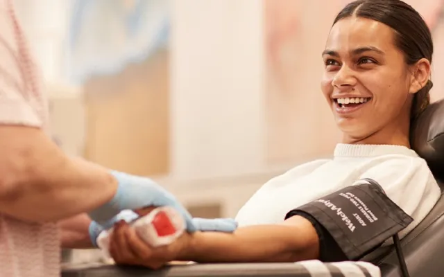 a woman seated in a chair during a donation smiling