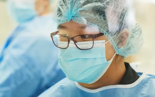 a lab technician wearing blue gown and mask