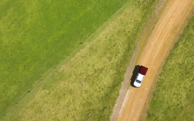 aerial photo of a field with a car driving on a dirt road within it