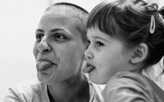 a mother and daughter laughing together and poking their tongues out