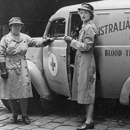Black and white image of two women standing in front of 1950s van that says "Australian Red Cross Society - Victorian Division - Blood Transfusion Service"