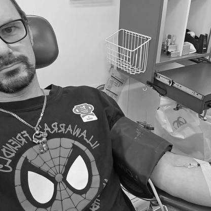 man taking a selfie whilst donating, showing the needle in his arm