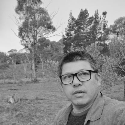 mnan taking a selfie in a field with trees in the background