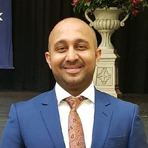 profile photo of anand wearing a blue suit jacket and orange tie