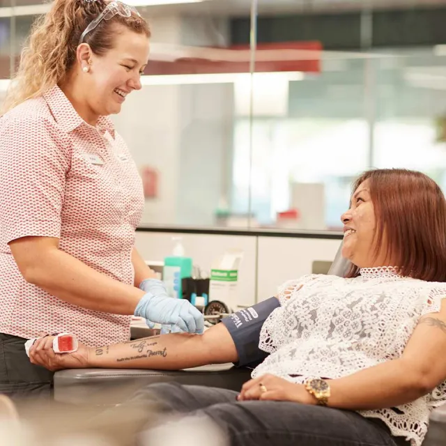 a woman giving a donation with a nurse standing next to her smiling